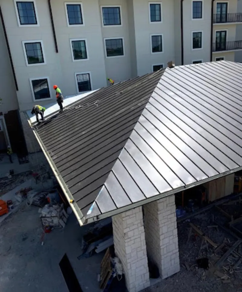 Crew installing standing seam metal roof panels on a commercial project in Maricopa
